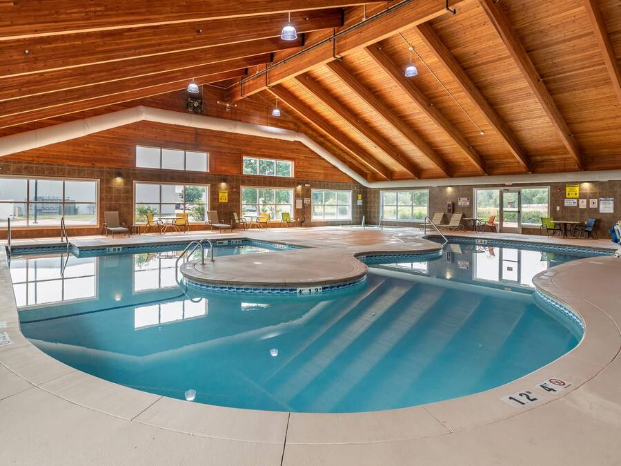 Une piscine intérieure dotée de plusieurs couloirs, de poutres en bois au plafond et de grandes fenêtres.