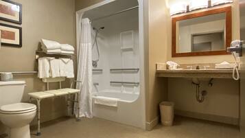 Un baño de hotel estándar con ducha, inodoro, lavabo y espejo.