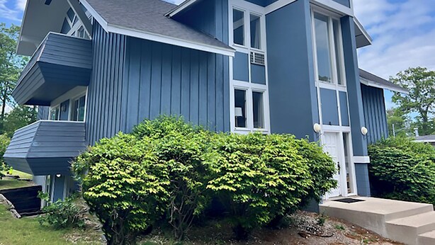 Ein modernes, zweistöckiges Haus mit blauer Fassade und weißem Dekor.