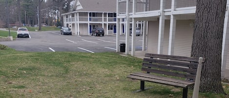 A bench in a grassy area with a building in the background.