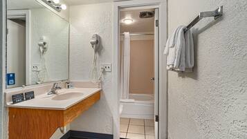 A bathroom with a sink, mirror, towel rack, and shower.