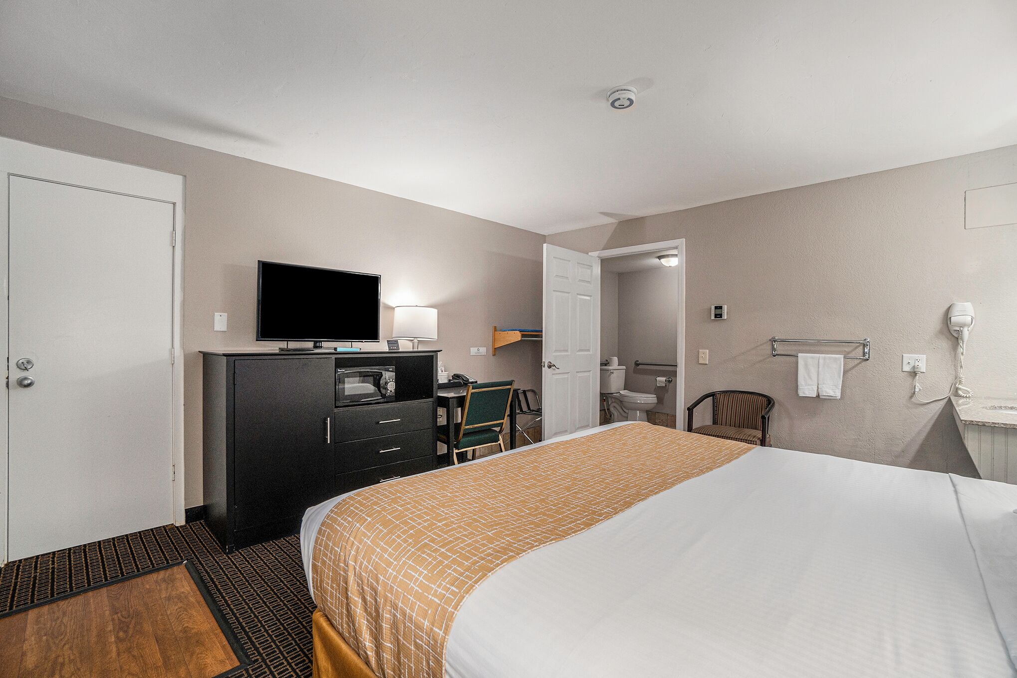 Ein Hotelzimmer mit einem Bett, einem Schreibtisch mit Computer, einem Fernseher und einem Badezimmer.