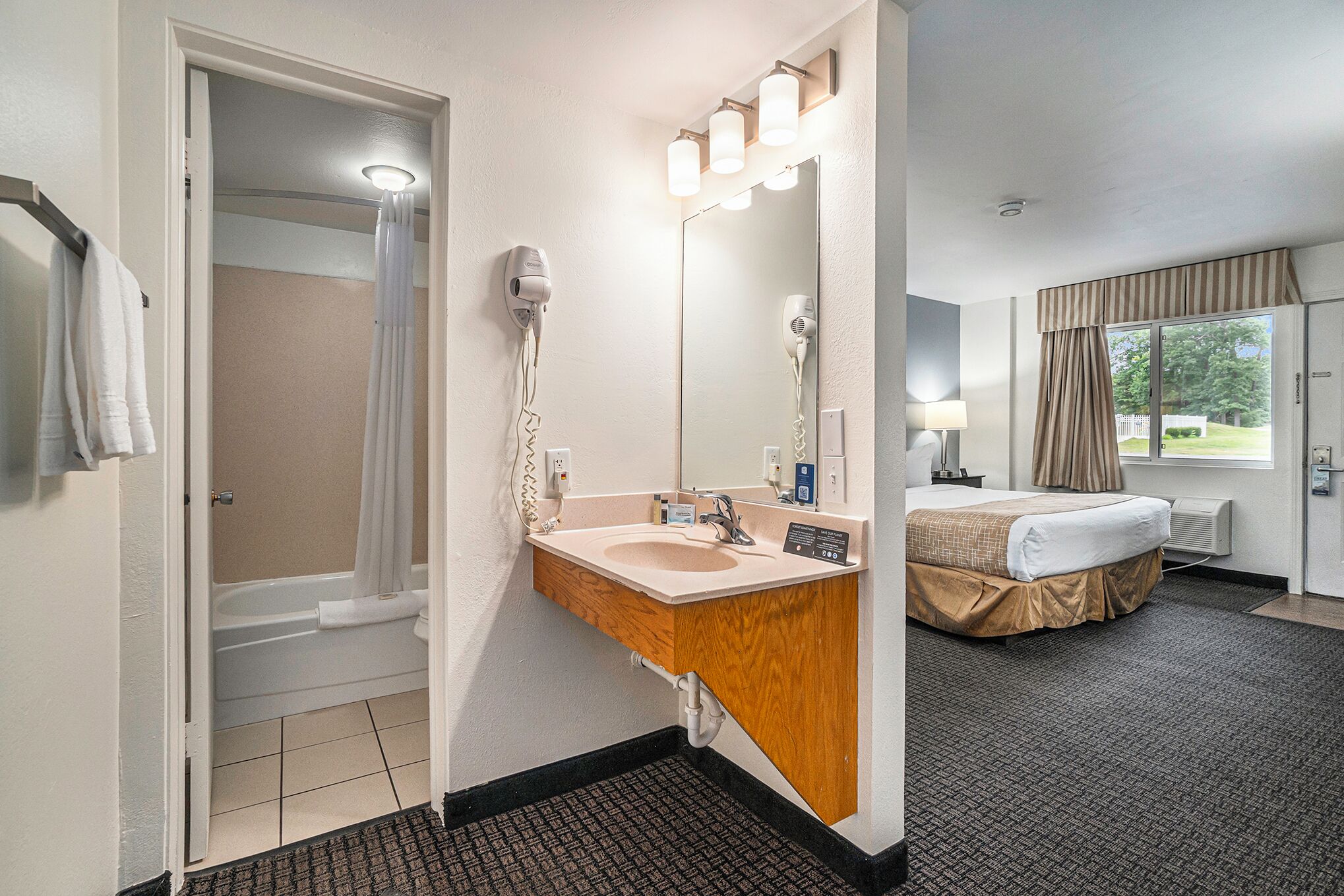 Een hotelbadkamer met een wastafel, spiegel en douche.