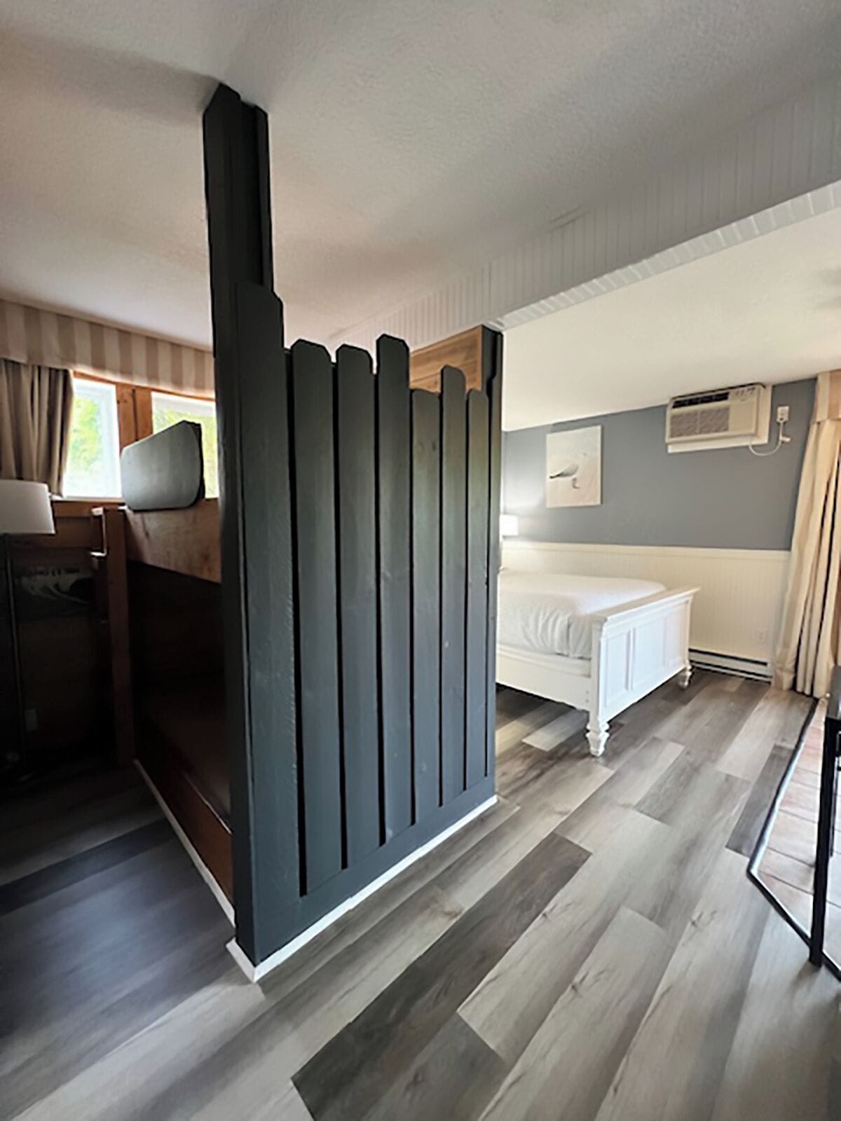 Een moderne slaapkamer met een bed, nachtkastje en een donkere scheidingswand.