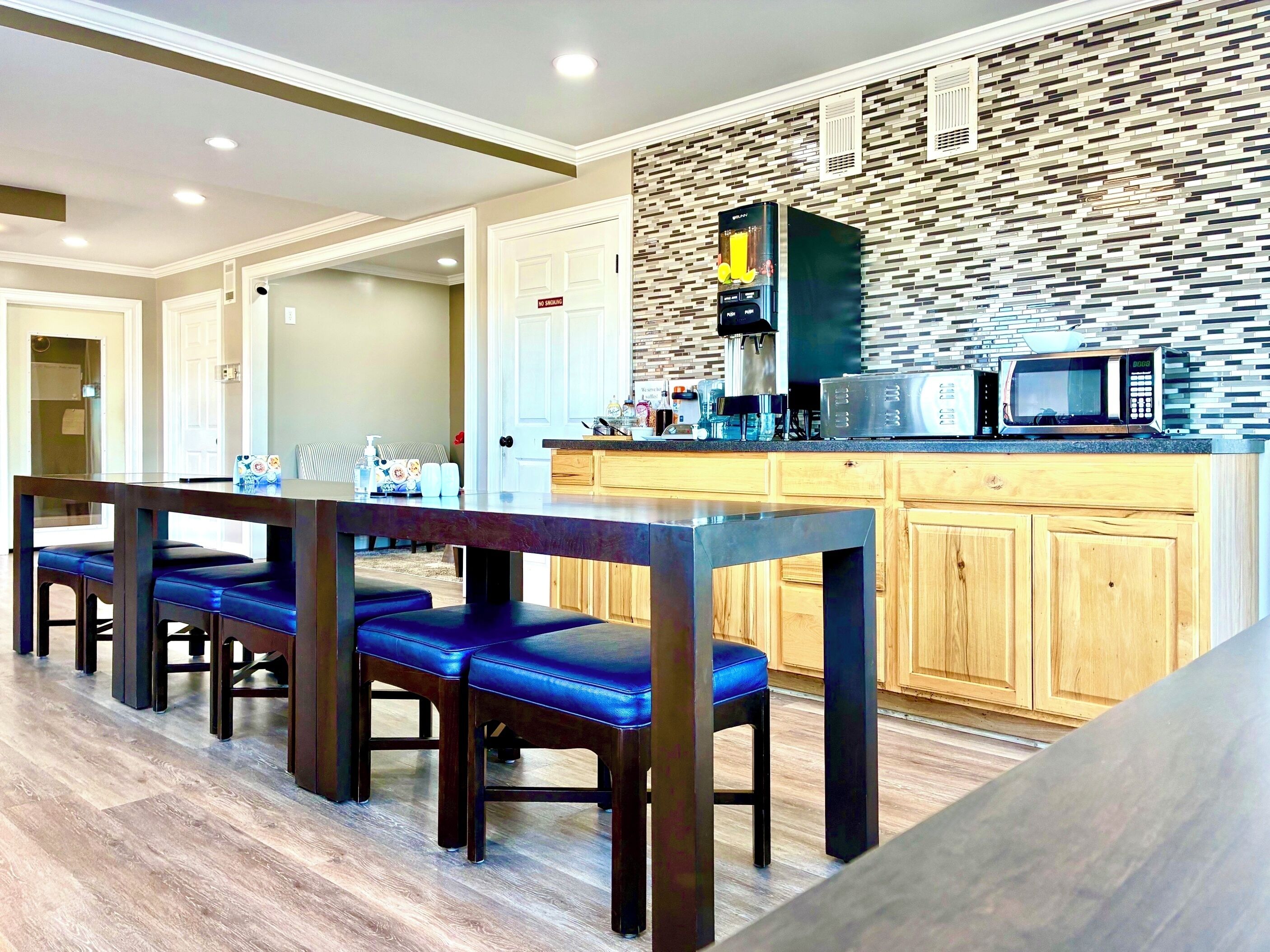 A modern kitchen with a stone backsplash, wooden cabinets, and a built-in microwave.