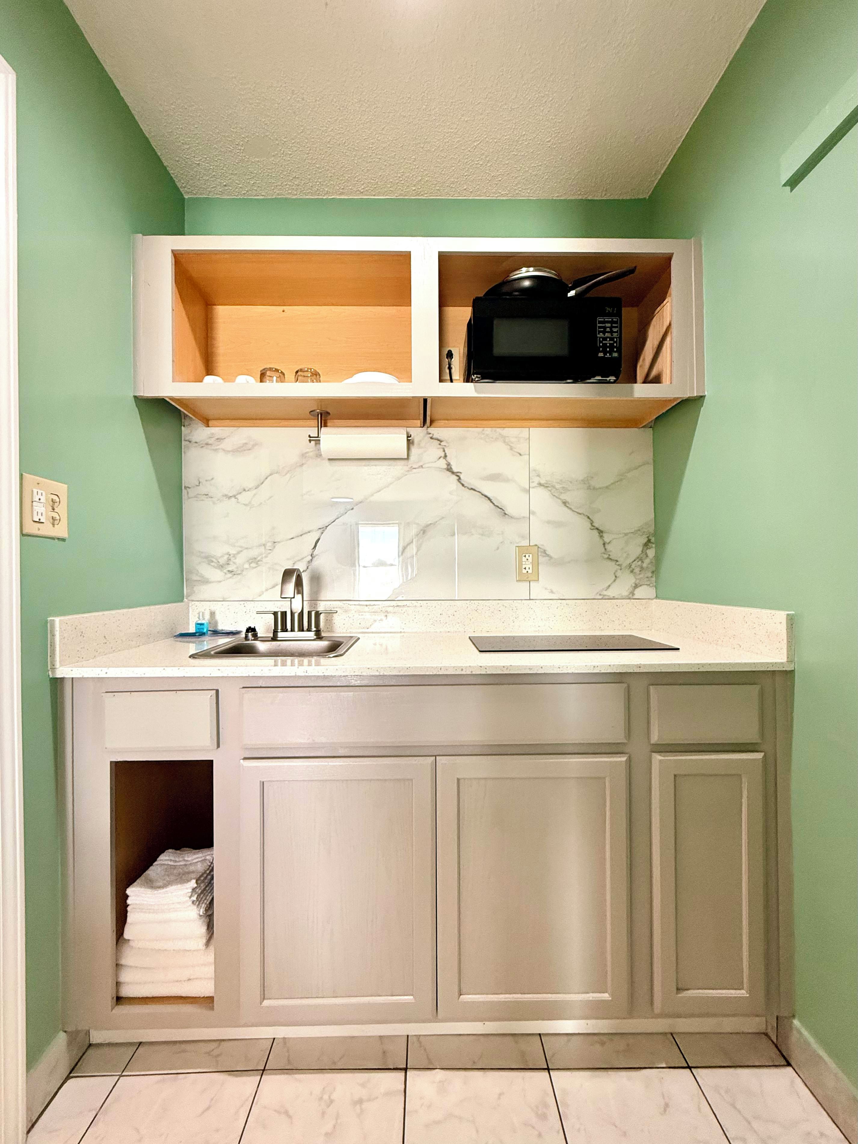 A kitchen with a marble backsplash, a microwave, and a sink.