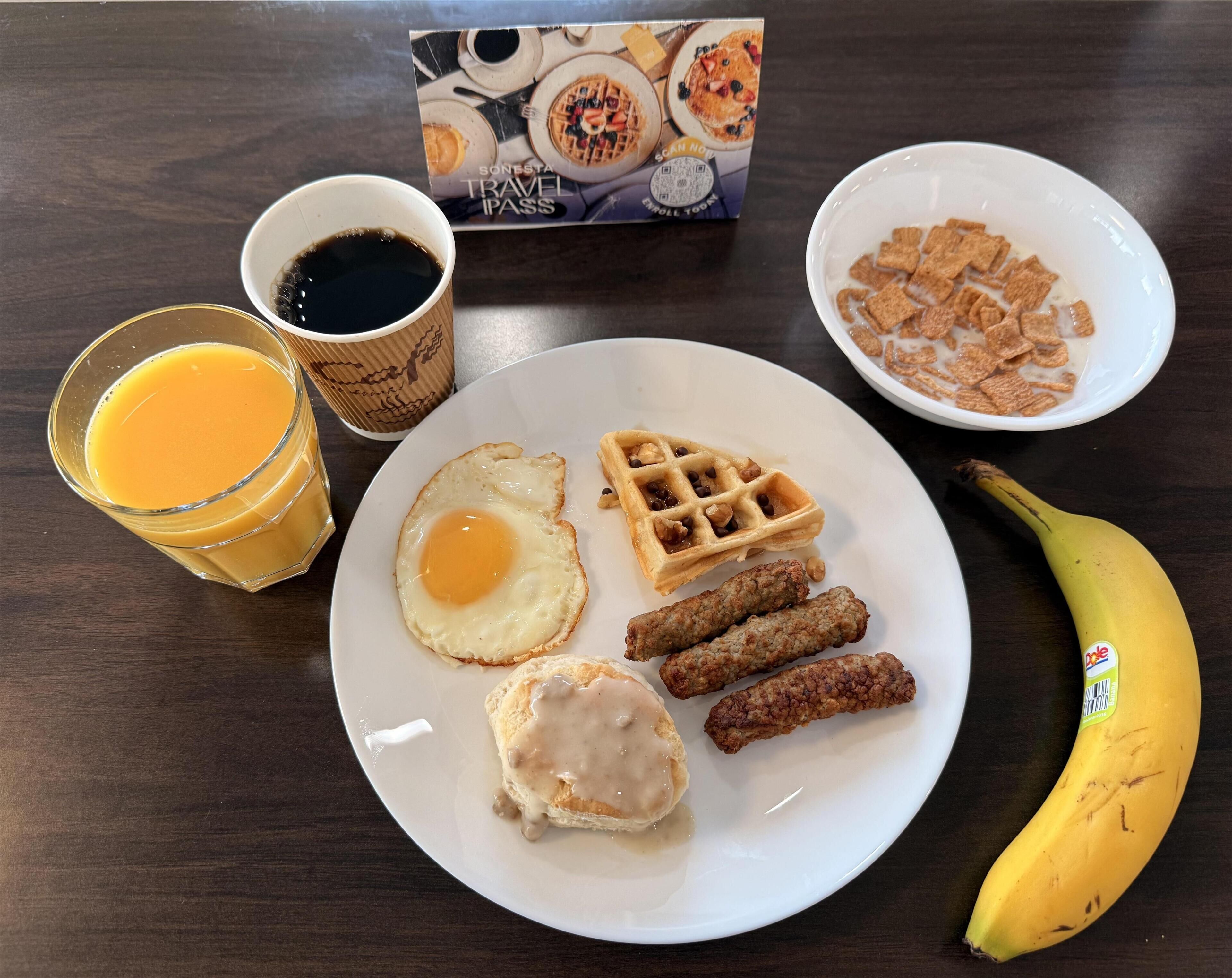 A breakfast plate with waffles, sausage, eggs, and a banana.