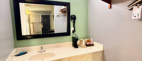 Un baño con lavamanos doble, espejo, secador de pelo y toallero.