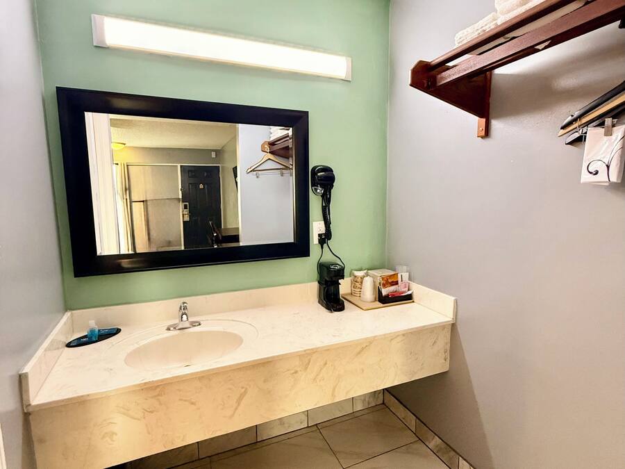Un baño con lavamanos doble, espejo, secador de pelo y toallero.
