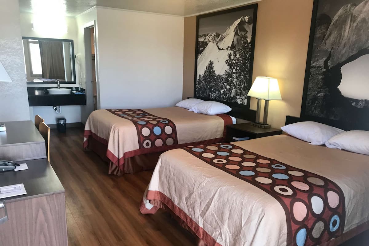 Una habitación de hotel con dos camas, un escritorio, un lavamanos y un espejo.