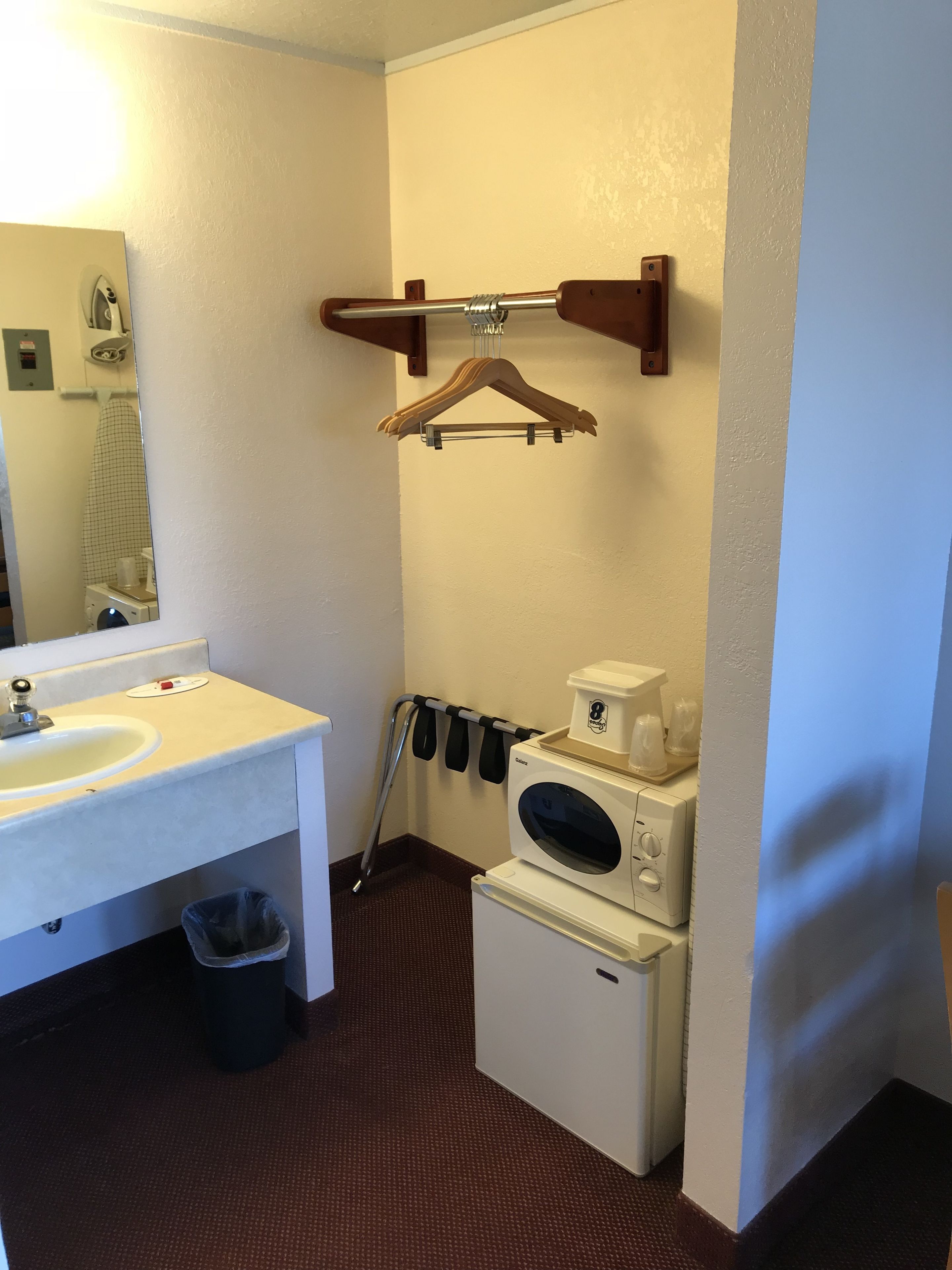 A small bathroom with a sink, mirror, towel rack, and a compact washer and dryer.