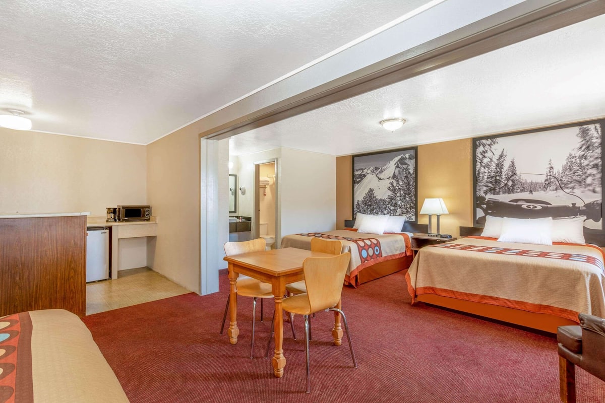 Habitación de hotel con una cama, un escritorio con silla, microondas y una pequeña kitchenette.