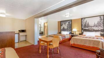 A hotel room with a bed, a desk with a chair, a microwave, and a small kitchenette.