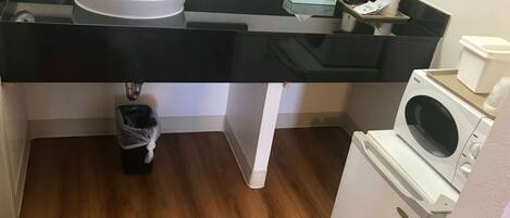 A bathroom with a black countertop, white sink, and a washing machine.