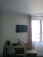 Una habitación con escritorio, silla y televisor de pantalla plana montado en la pared.