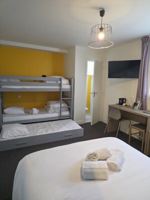A hotel room with a bunk bed, a desk with a chair, a flat-screen TV, and a bed with towels.