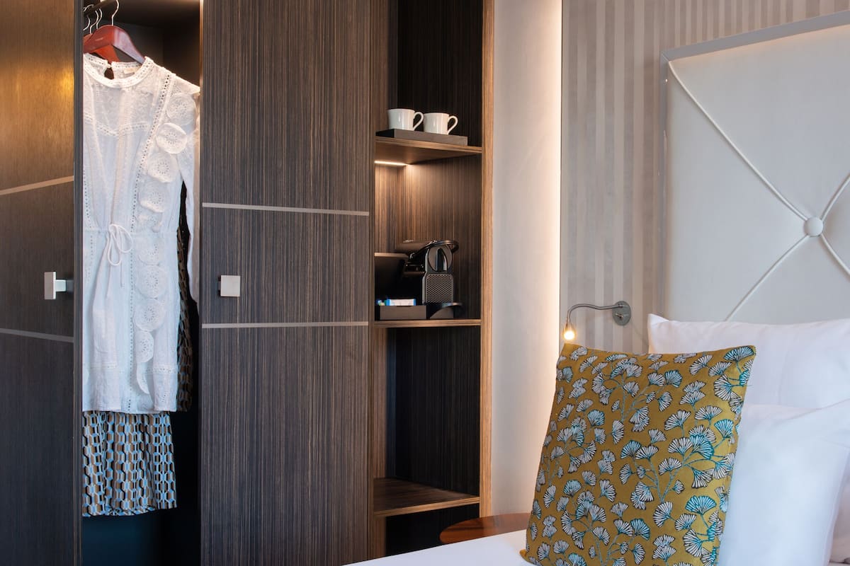 A hotel room with a bed, a wardrobe, a bedside table, and a nightstand.