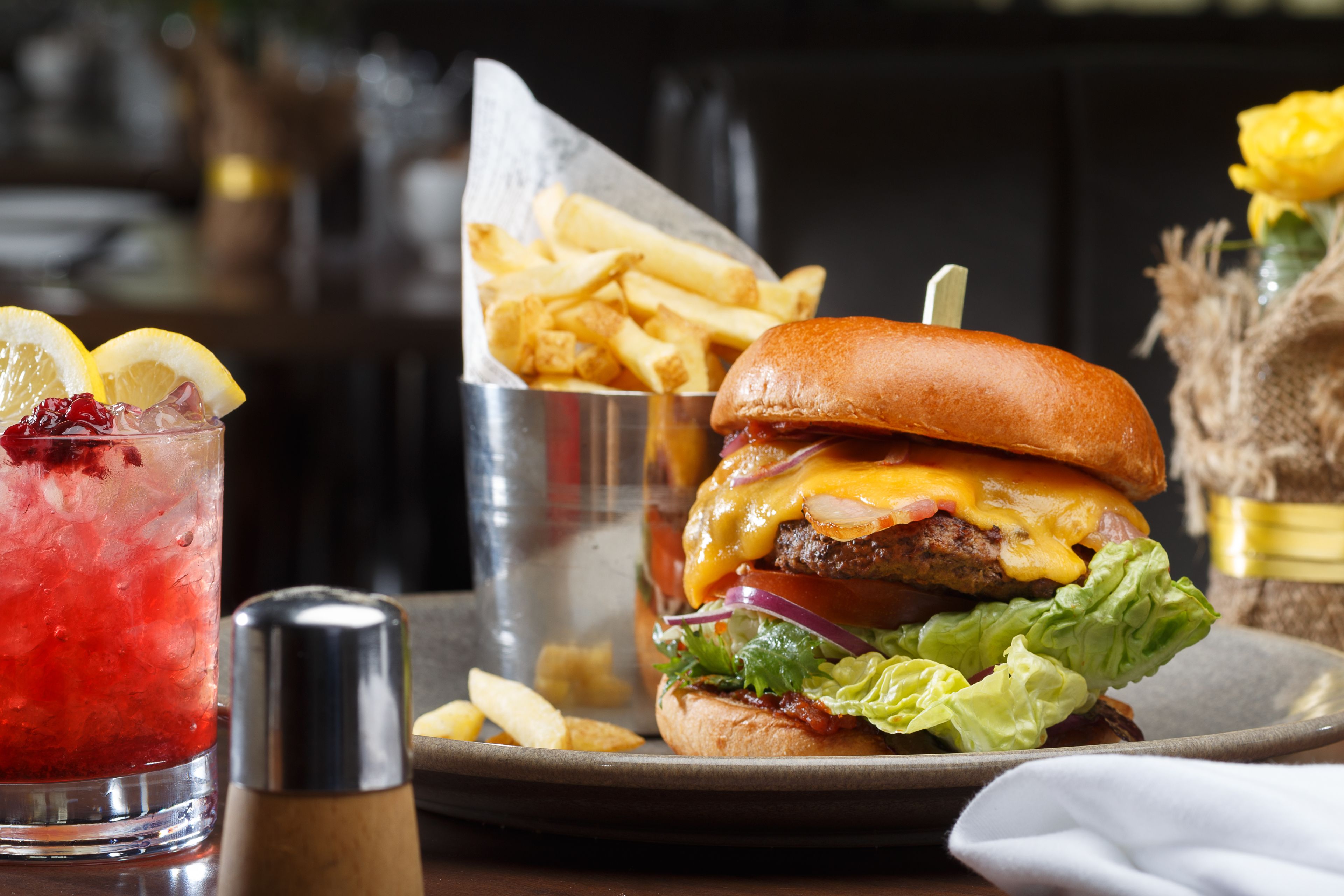 A burger with fries and a drink on a table.