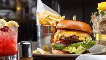 A burger with fries and a drink on a table.