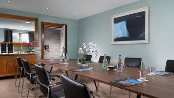 A conference room with a long table, chairs, and a coffee station.