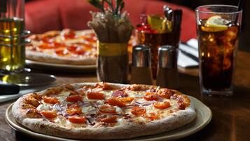 A pizza with toppings on a plate, a glass of iced tea, and condiments on a table.