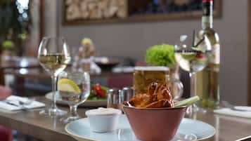 A dining table with a bowl of food, a glass of white wine, and a bottle of olive oil.