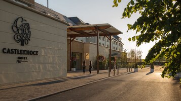 Exterior del Hotel Castleknock, con fachada moderna, un acceso cubierto y una zona pavimentada con ladrillos.