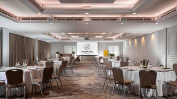 A conference room with round tables, chairs, and a presentation screen.