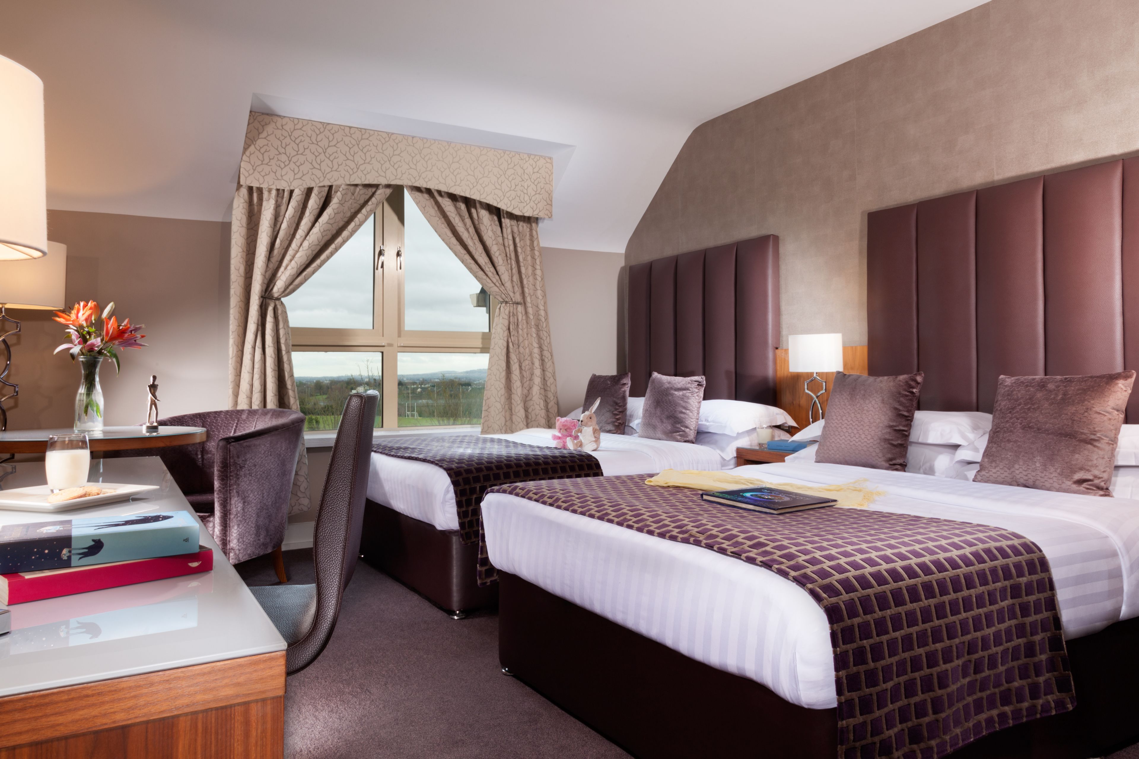 Ein Hotelzimmer mit zwei Betten, einem Schreibtisch und einem Stuhl.