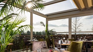 Un restaurante con mesas redondas, sillas y vistas al campo.