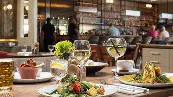 A restaurant setting with a table set for a meal, including plates of food, glasses of wine, and a beer mug.