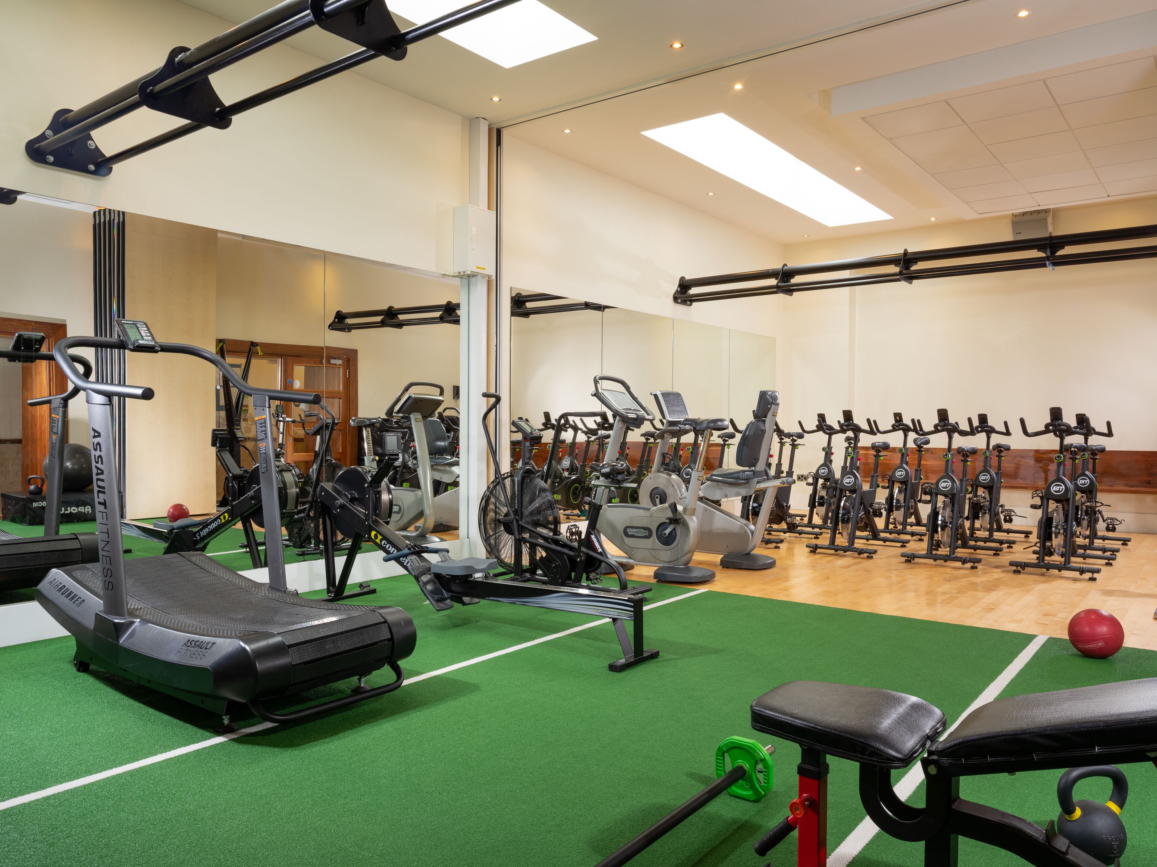 Ein Fitnessstudio mit verschiedenen Trainingsgeräten, darunter Laufbänder, Ergometer und Kraftgeräte.