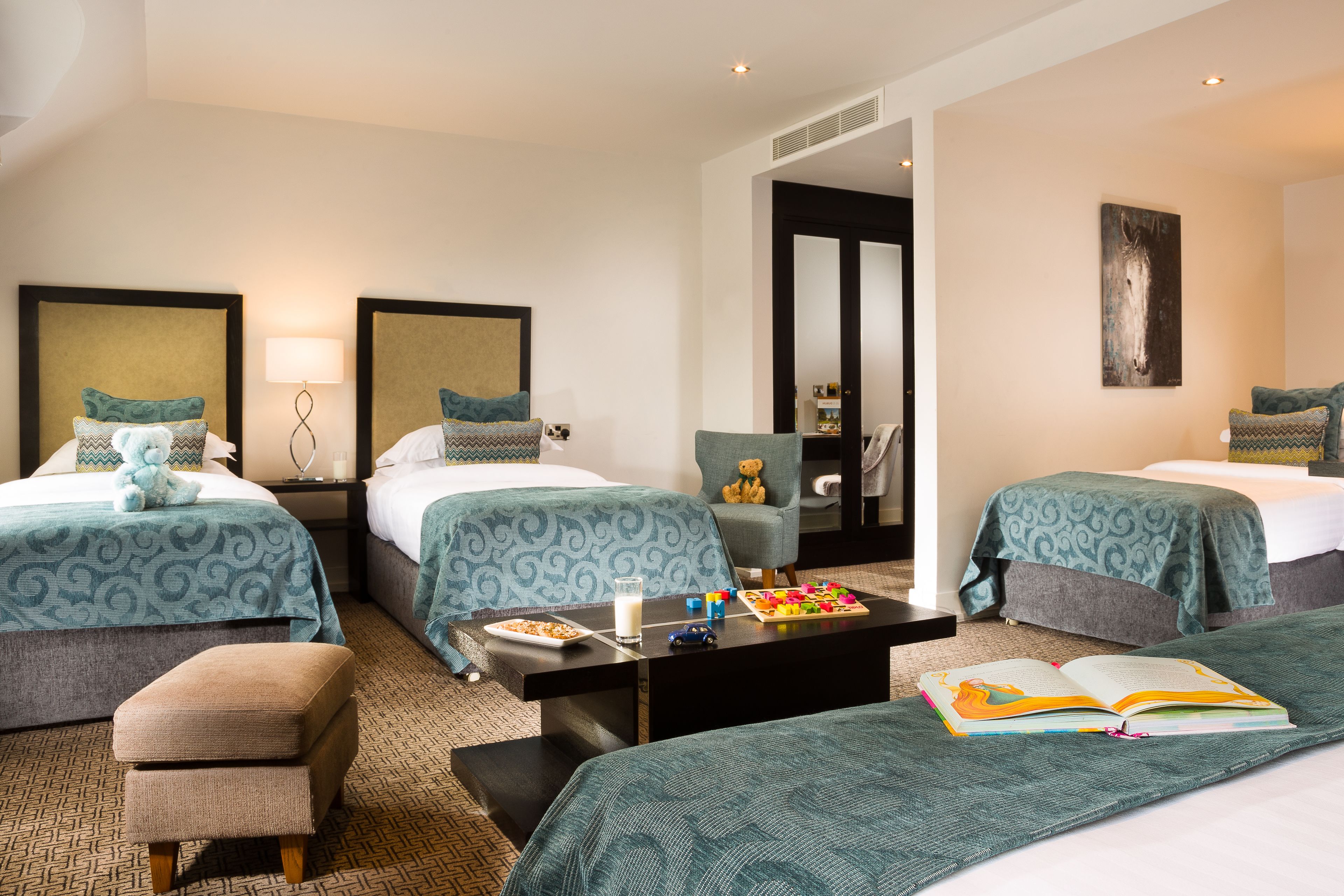 A hotel room with two beds, a sofa, a coffee table, and a chair.