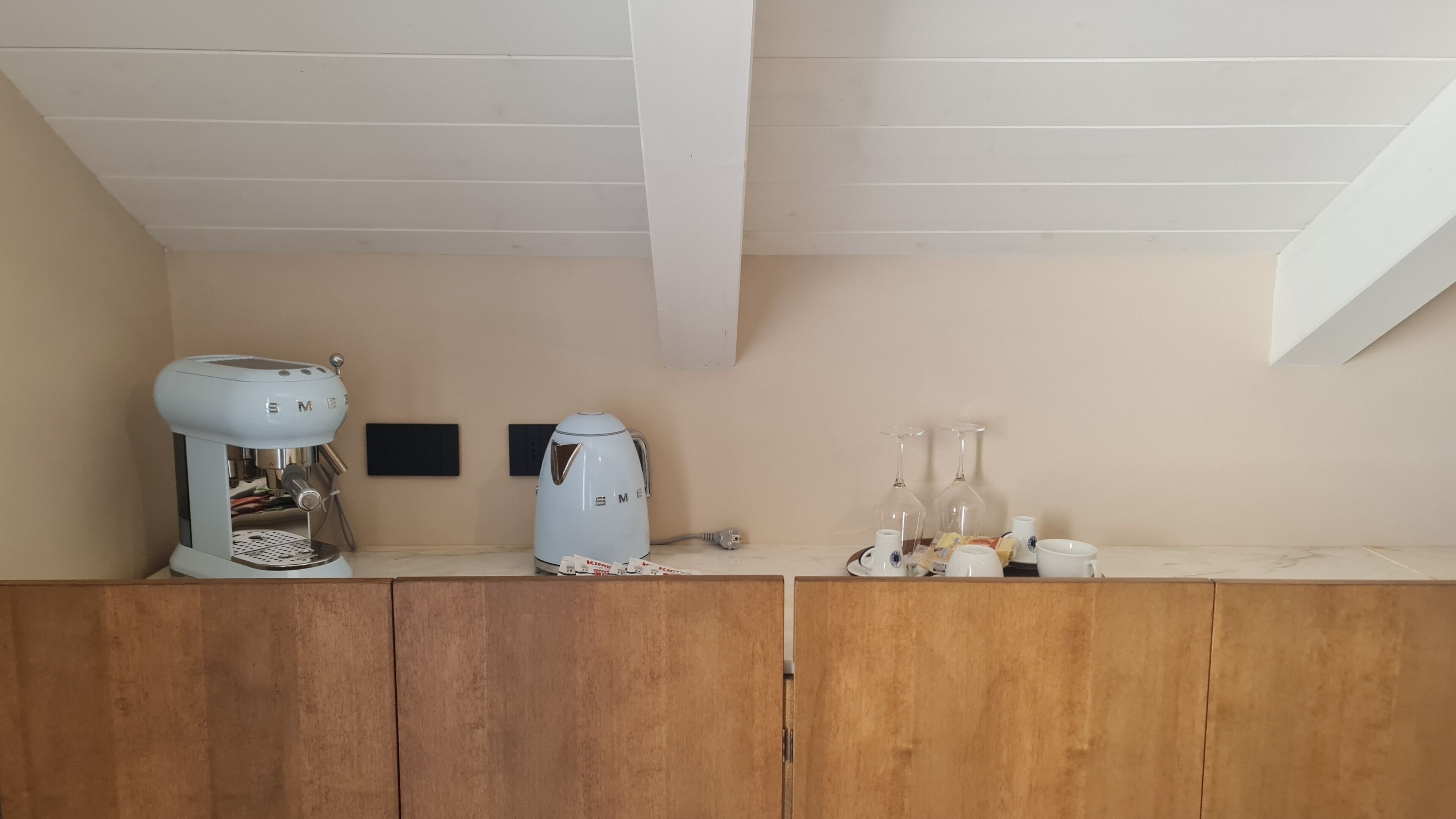 Une cuisine équipée d’une machine à café, d’une bouilloire et d’un ensemble de verres à vin posés sur le comptoir.