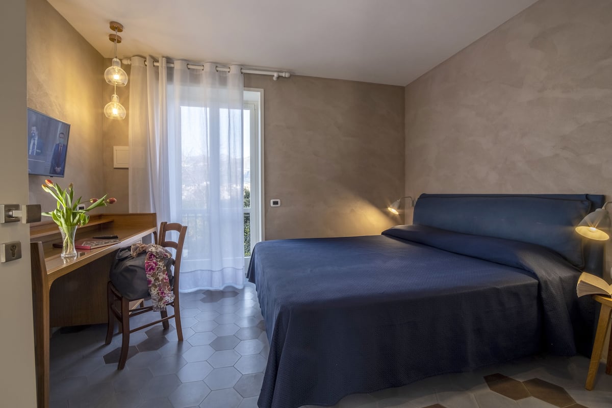 Un dormitorio moderno con cama, escritorio, silla y televisor en la pared.