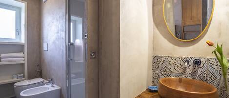 A bathroom with a toilet, bidet, and a wooden sink with a mirror above it.
