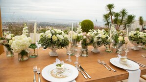 A table set for a meal with white plates, silverware, and glass candle holders with flowers. - Hotel Panorama (Pylaia-Chortiatis)