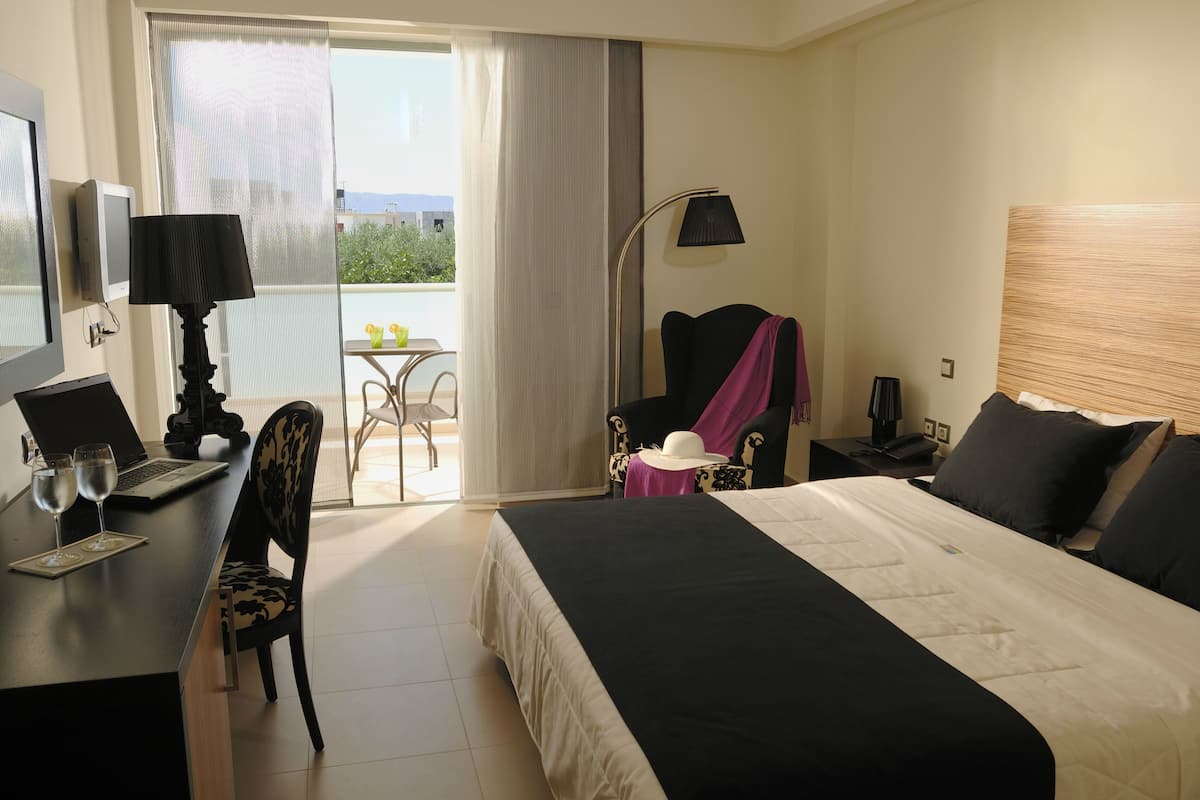 Ein Hotelzimmer mit Bett, Schreibtisch, Stuhl und einem Balkon mit Tisch und Stühlen.