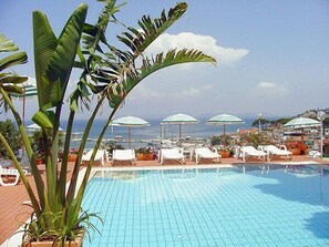 A pool area with lounge chairs and umbrellas, overlooking a body of water. - Pithaecusa (Casamicciola Terme)