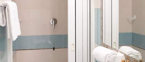Un baño moderno con cabina de ducha de vidrio, un lavabo blanco y un tocador con espejo.