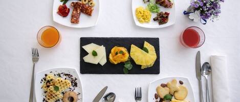 A breakfast setting with various dishes, including waffles, eggs, and fruits, arranged on plates and a slate board.