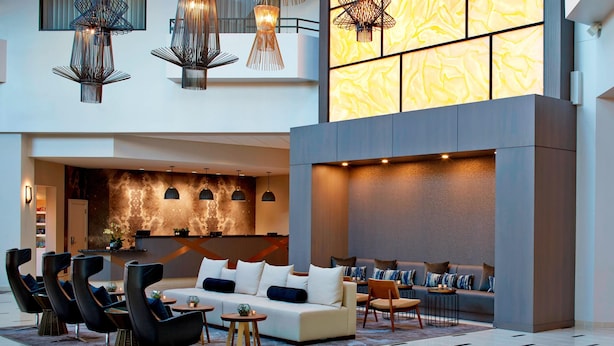 Un hall d’entrée spacieux, doté d’un canapé moderne, de chaises noires et d’un coin repas.