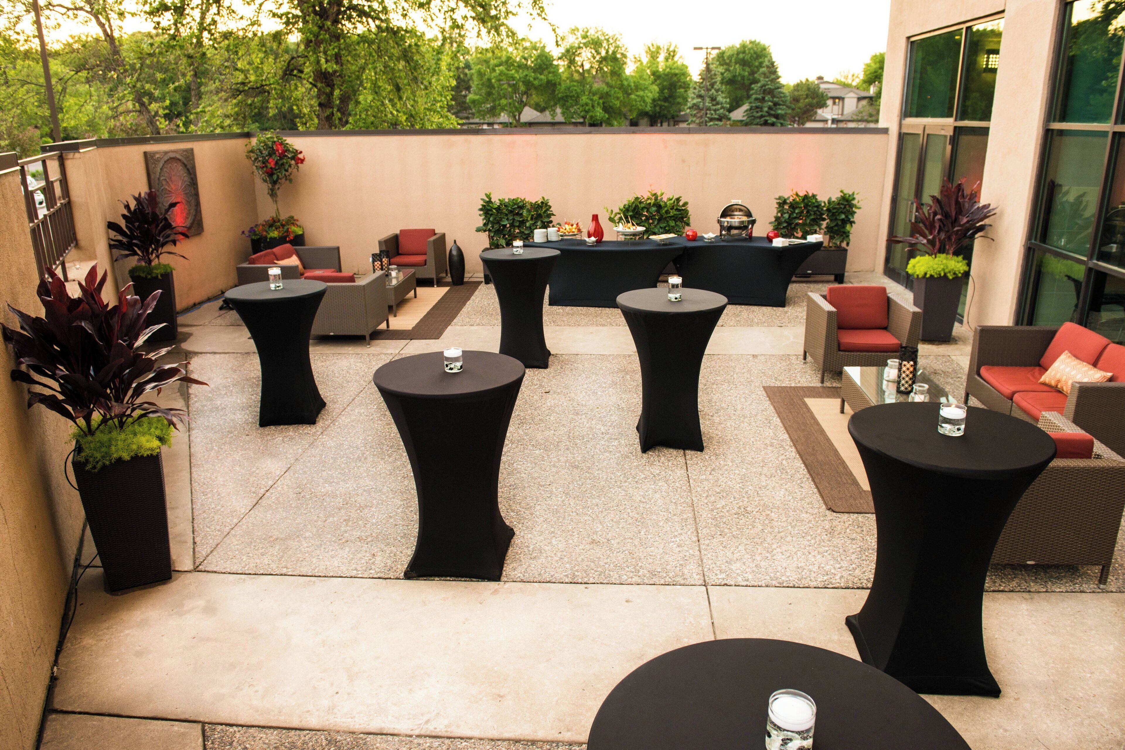 An outdoor patio area with round black tables and red cushioned seating.