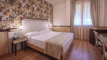 Habitación de hotel con cama, mesita de noche, lámpara, escritorio, silla y pared con diseño.