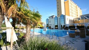 Un hôtel doté d’une piscine, de palmiers et d’espaces de détente en plein air.
