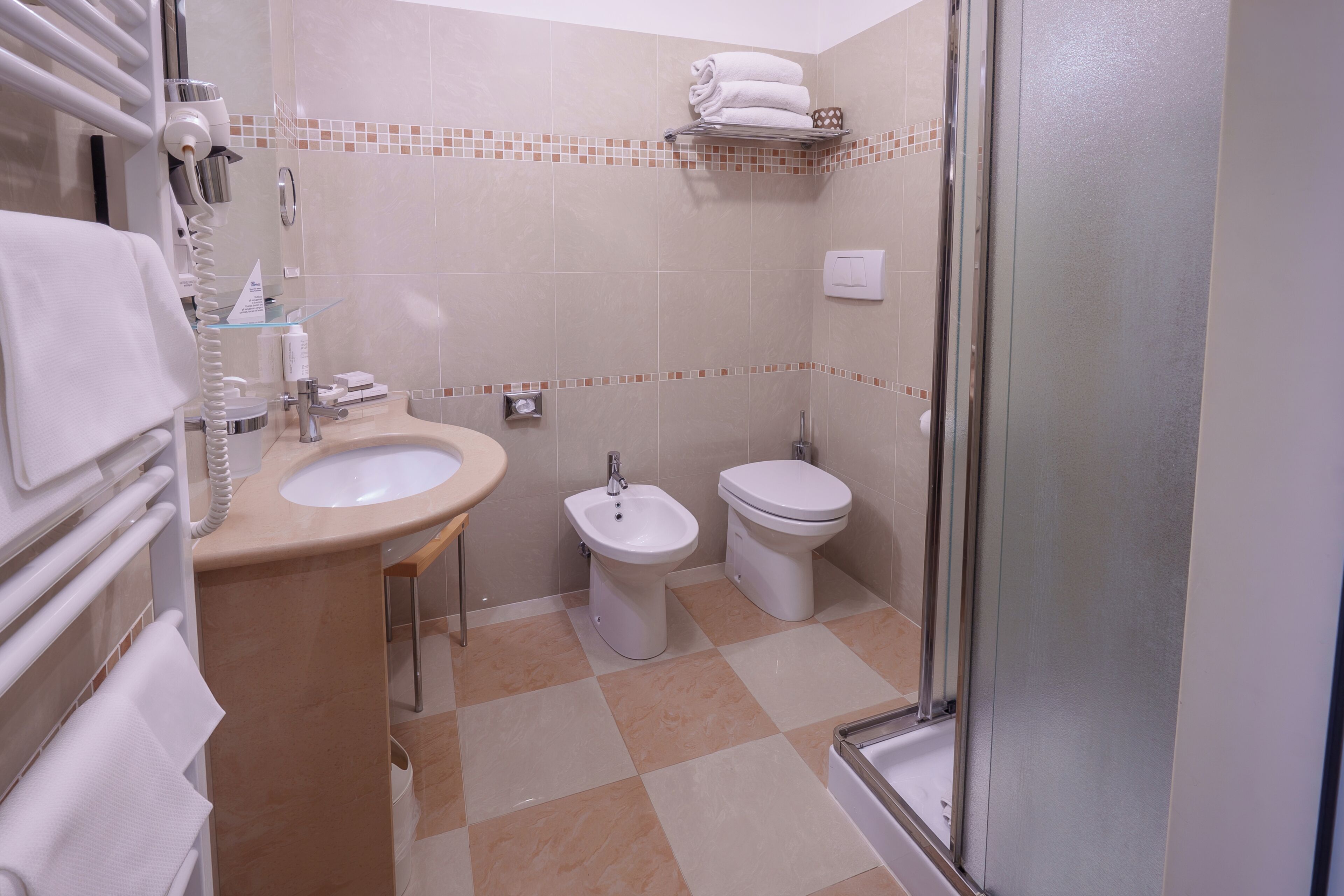 Un baño con lavamanos, bidé, inodoro y cabina de ducha de vidrio.