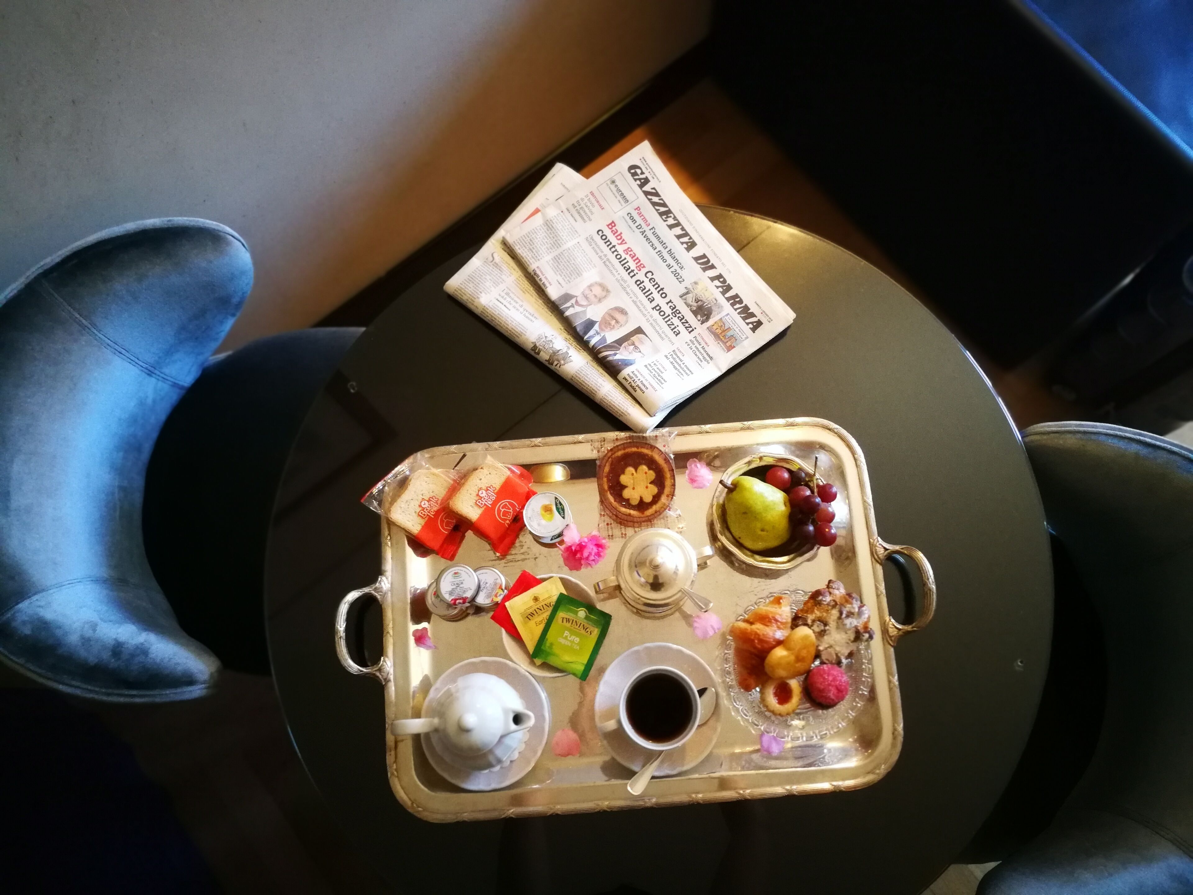 A tray with food and drinks on a table, a newspaper, and two chairs.