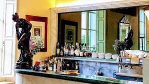 Un espace bar doté d’un comptoir en marbre, de bouteilles et d’un miroir décoratif.