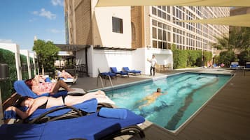 Relax by the pool surrounded by lounge chairs and a wooden deck.