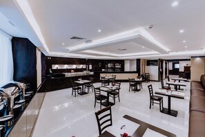 A modern restaurant with a bar area, multiple dining tables, and a buffet setup. - Panorama Deira (Dubai)